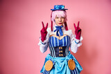 beautiful chic female cosplayer showing peace gesture and looking at camera on pink backdrop