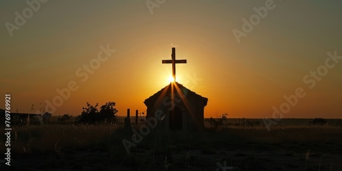 A cross silhouette against the setting sun outside a rural church. 
