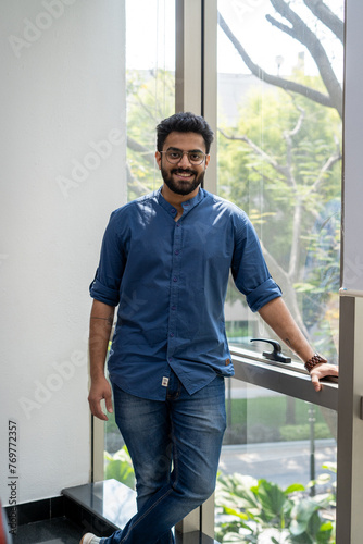 Portrait Of Happy and Confident Young Indian Man In A Corporate Office, Enjoying Creative Work Opportunities, Wearing Eyeglasses and Smiling