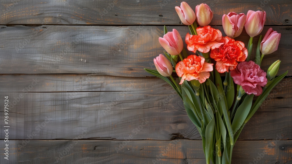 A bouquet of fresh tulips and carnations arranged on a rustic wooden background with space for text.