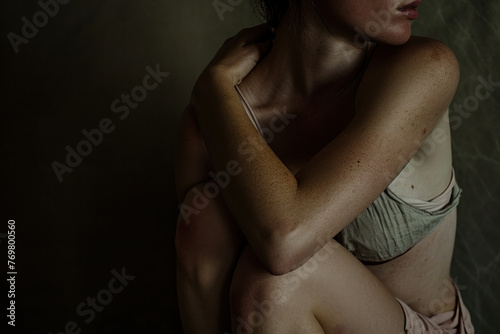 Young woman in a bikini sitting on the floor with her back to the camera and hands on her knees