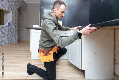 Older man disassembling apartment kitchen out of service