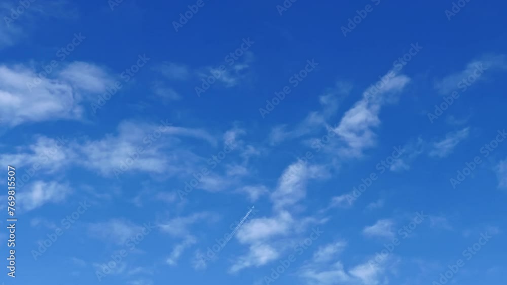 An airplane with jet contrail flying over the clouds in the blue sky. Cloudscape with blue sky background. An airplane with jet contrail flying over the clouds in the blue sky. Cloudscape with blue sky background.