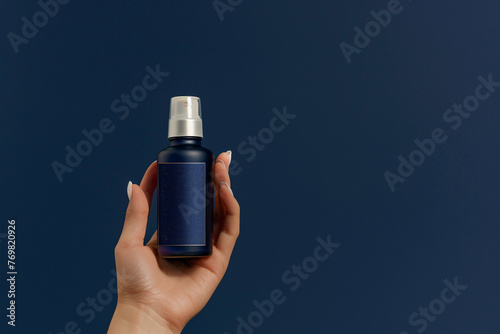 Hand holding luxury elegant skincare product bottle against a deep sapphire blue isolated solid background, conveying depth and luxury,