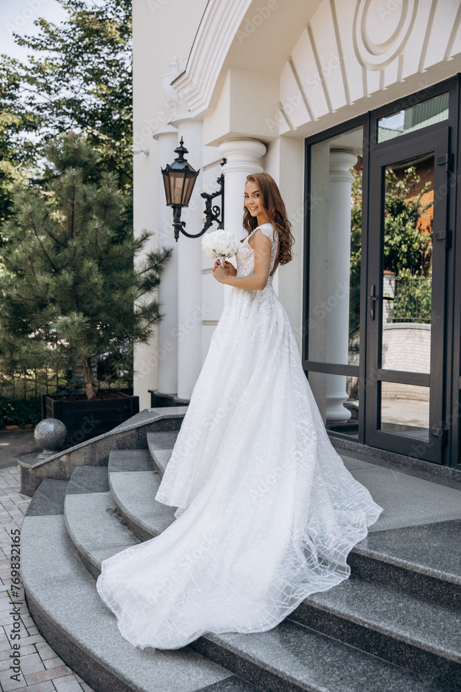 Luxury portrait of a red-haired bride with a bouquet of white peonies in a lush dress
