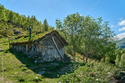 old hut along the hiking trail towards the spectacular Seven Sisters waterfall through deep green forest along the Geirangerfjord  Norway on a sunny day.