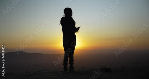 Silhouette of youn mexican girl moving her body in the sunset, in a mountain