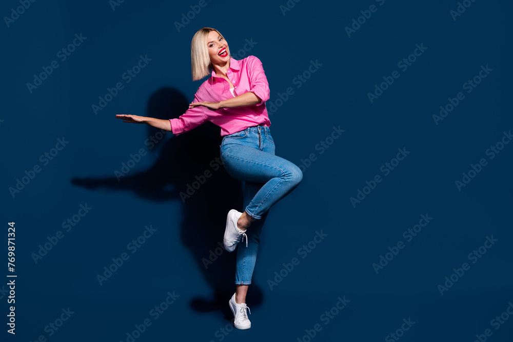 Full length photo of satisfied adorable woman wear stylish shirt denim pants dancing having fun isolated on dark blue color background