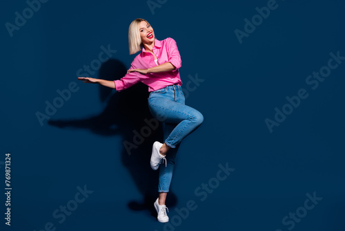 Fototapeta Naklejka Na Ścianę i Meble -  Full length photo of satisfied adorable woman wear stylish shirt denim pants dancing having fun isolated on dark blue color background