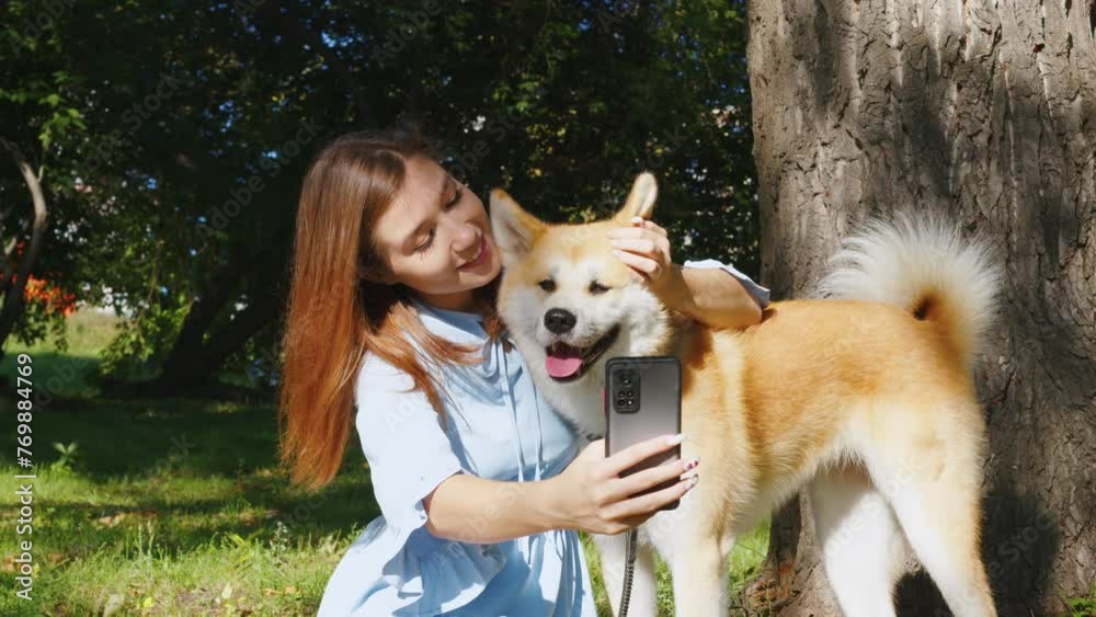 Cute girl takes selfie on smartphone with her dog in park. Young lady ...