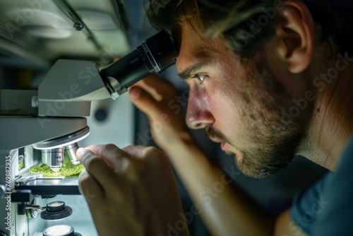 A man, a Greenpeace biologist, is closely examining a sample of plankton under a microscope for research purposes