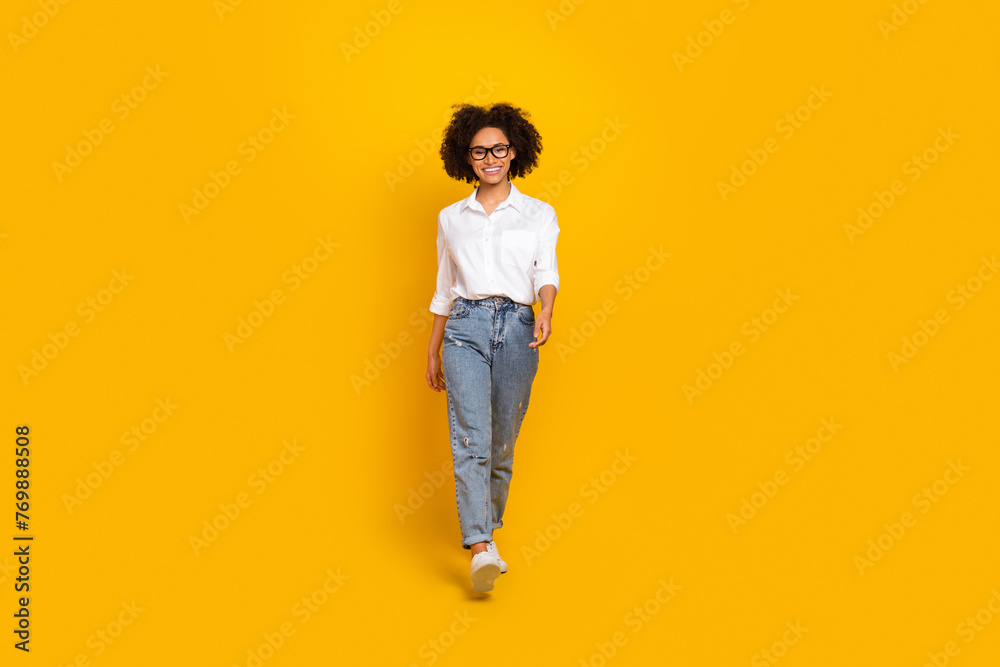 Full length body size view of attractive smart cheerful girl assistant going isolated over bright yellow color background Full length body size view of attractive smart cheerful girl assistant going isolated over bright yellow color background
