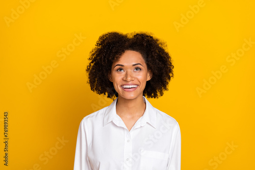 Portrait of attractive cheerful wavy-haired girl looking up copy space isolated over bright yellow color background