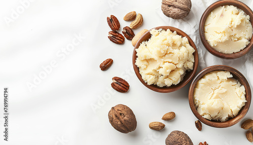Shea butter in spoon and bowls on white wooden background