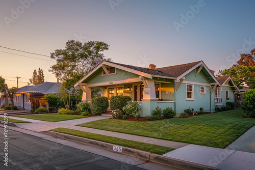 Early evening as the sun sets, casting a warm hue over a light green Craftsman style house, quiet suburban street winding down from the day's activities, peaceful and calm atmosphere