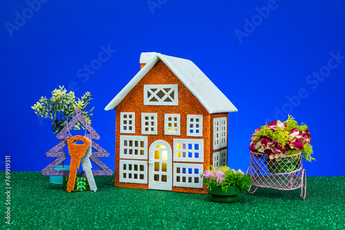 One orange house with flowers and a Christmas tree with keys around on a blue background