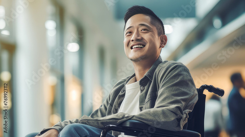 Happy smiling young Asian guy student in a wheelchair in the foyer of an educational institution.