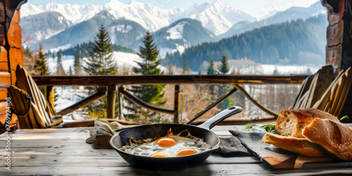 Breakfast on the veranda in a chateau made from fried eggs on a cast iron frying pan, next to fresh country bread, a magnificent view of the snow-capped mountain peaks photo