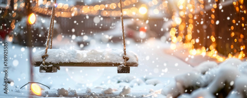 A small, snow-covered wooden swing, with blurred holiday lights in