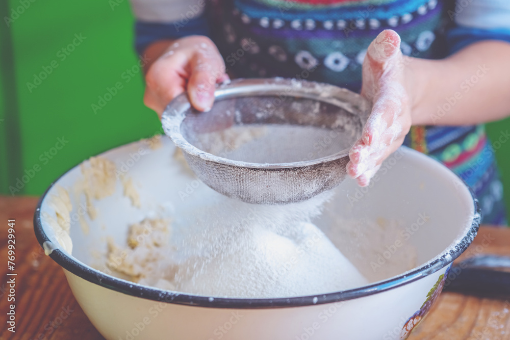 Young female cook hands kneading dough, sprinkling piece of dough with white wheat flour. Food, the art of cooking and handmade concept. Horizontal image.