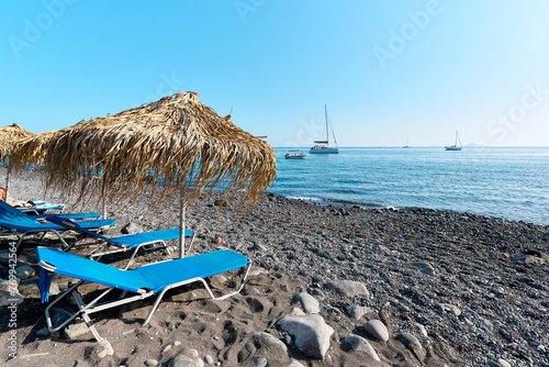 Fototapeta Naklejka Na Ścianę i Meble -  View with beach and boats at the black sand beach of Akrotiri that is known locally as Mesa Pigadia beach. Greek Islands, Santorini, European Vacation