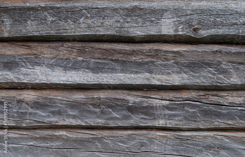 Texture of old weathered gray wall made of hewn logs