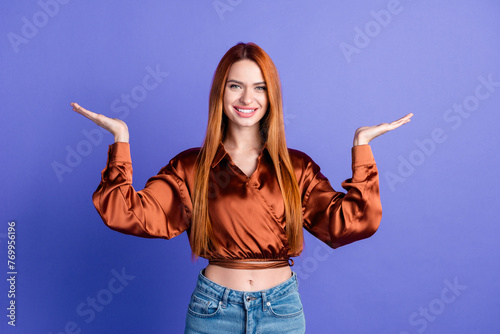 Portrait of nice young woman hands demonstrate empty space wear brown shirt isolated on purple color background © deagreez