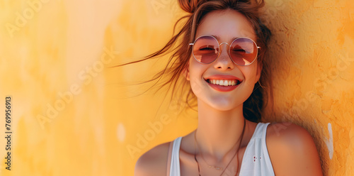Portrait of a young smiling woman on a yellow background on a sunny summer day. Copy space photo