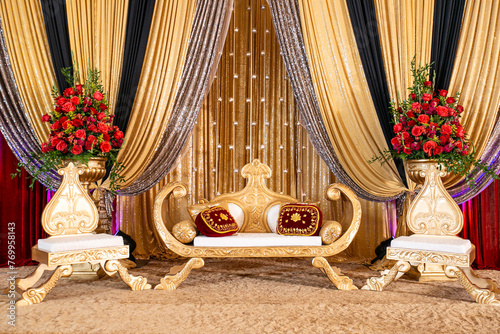 Gold red and ivory Indian wedding stage with rose arrangements photo