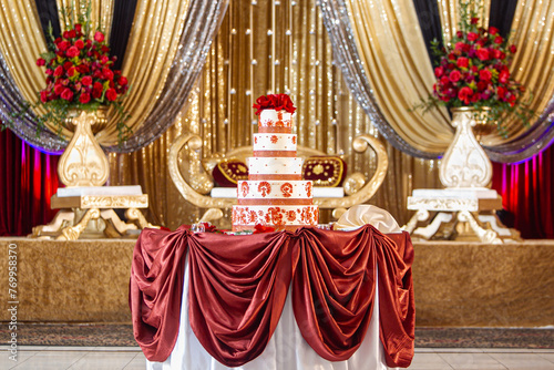 Gold themed Indian wedding stage with tiered wedding cake table