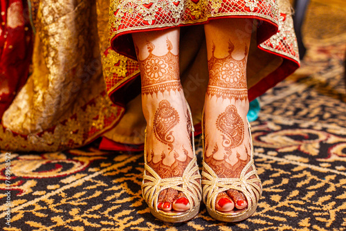 Indian bridal henna tattoos on feet with golden shoes photo