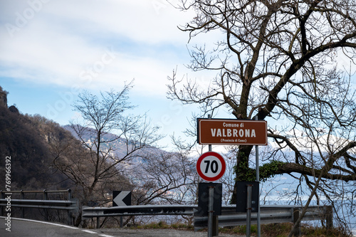 Driving car along shores of Lake Como in Northern Italy, spring sunny days, views of alpine mountains, water and villages