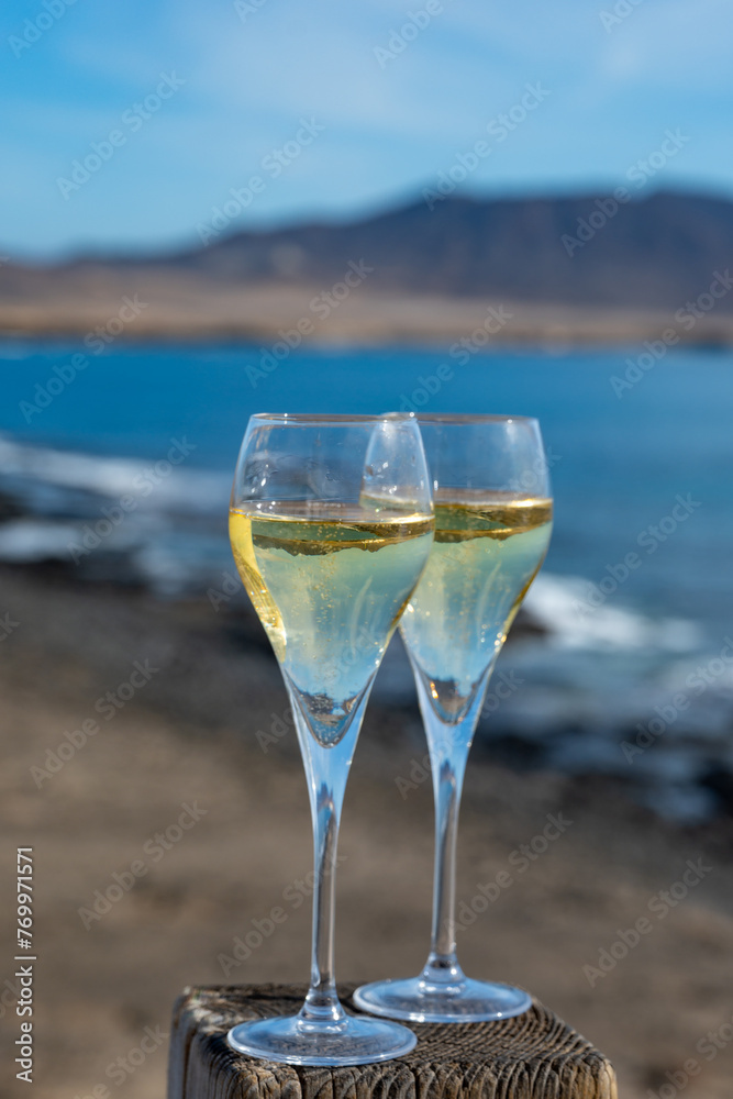 Pouring a glass of champagne on vacation, south of Fuerteventura, Canary islands, blue ocean, mountains Pouring a glass of champagne on vacation, south of Fuerteventura, Canary islands, blue ocean, mountains