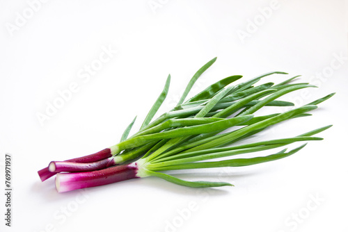 Red onions on a white background. Fresh green onion feathers.