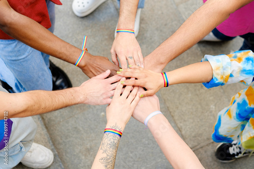 A group of people with rainbow bracelets on their hands are holding hands in a circle. Concept of unity and togetherness among the group