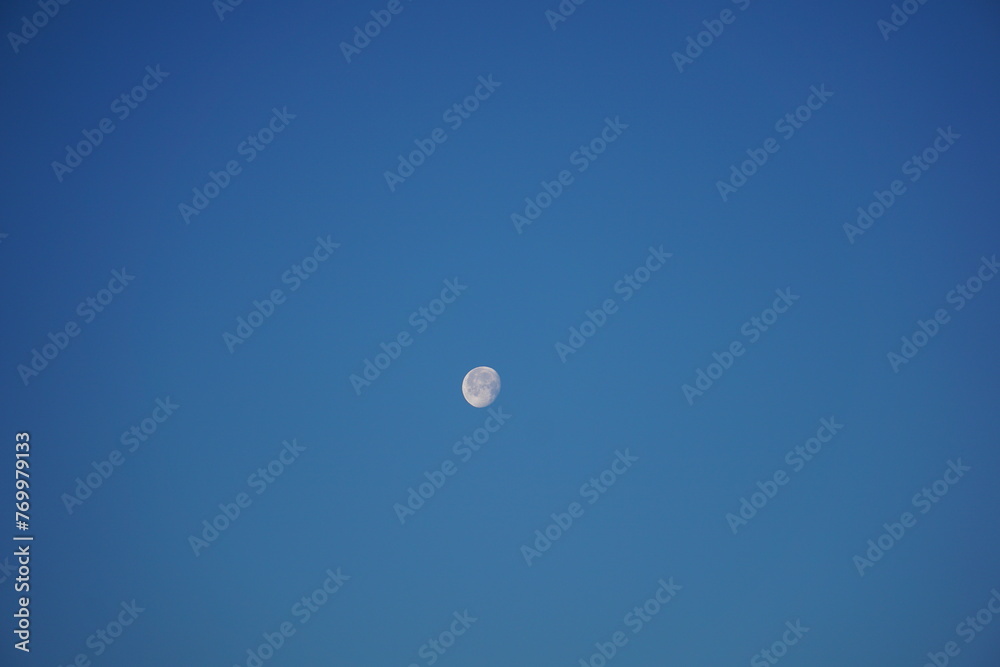 Glowing moon against an early morning, clear blue sky. Waning Gibbous. Glowing moon against an early morning, clear blue sky. Waning Gibbous.