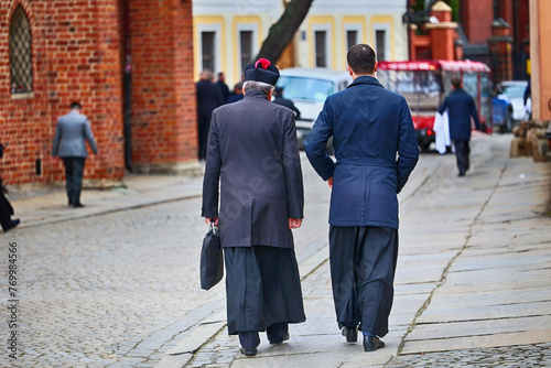 Ksiądz katolicki w czarnej sutannie idzie na mszę świętą