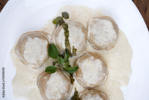 Italian food. Pasta. Top view of mozzarella cheese and ham sorrentinos with cream and pesto sauce, in a white dish. photo