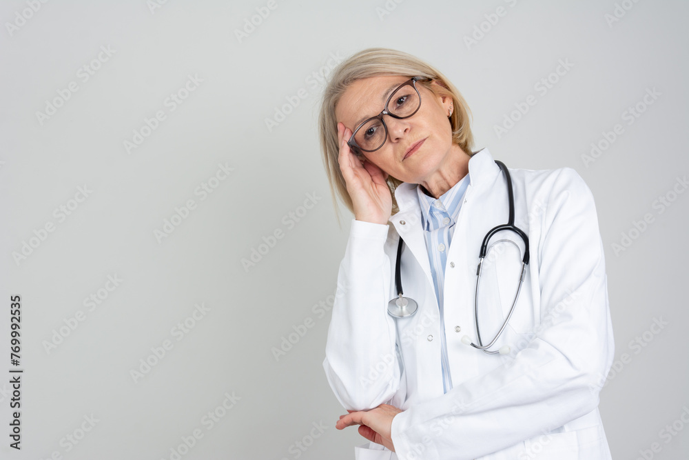 Migraine and headache people - Doctor stressed. Stressed And Overworked Female Doctor Isolated on Grey Background. Tired Caucasian female doctor. Migraine and headache people - Doctor stressed. Stressed And Overworked Female Doctor Isolated on Grey Background. Tired Caucasian female doctor.