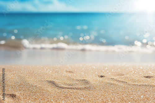 Close-up of sandy beach textures with a softly blurred ocean backdrop and glistening sunlight particles