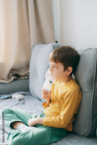 little boy sits with an inhalation mask during cough and bronchitis. Treatment with an inhaler at home