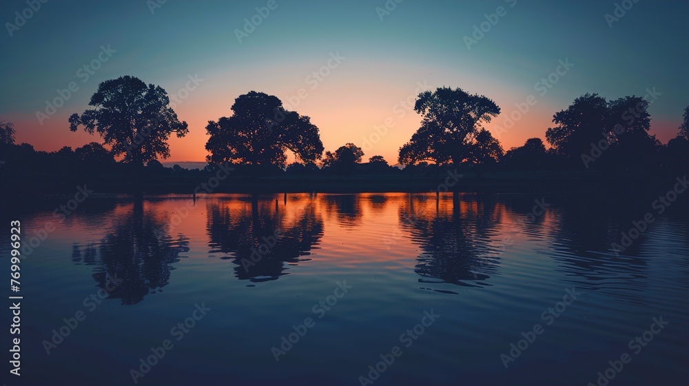 Twilight settling over a tranquil lakeside, with the silhouettes of trees against the fading light.