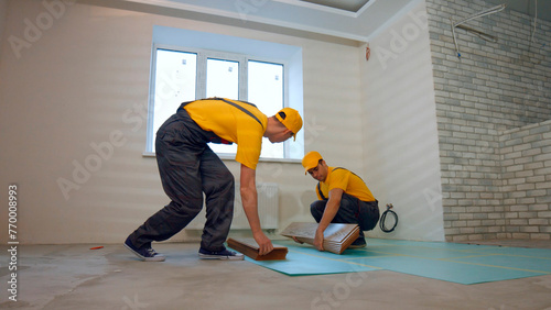 Builders are laying the floor in a new house. Wooden laminate for the floor. © DenisProduction.com