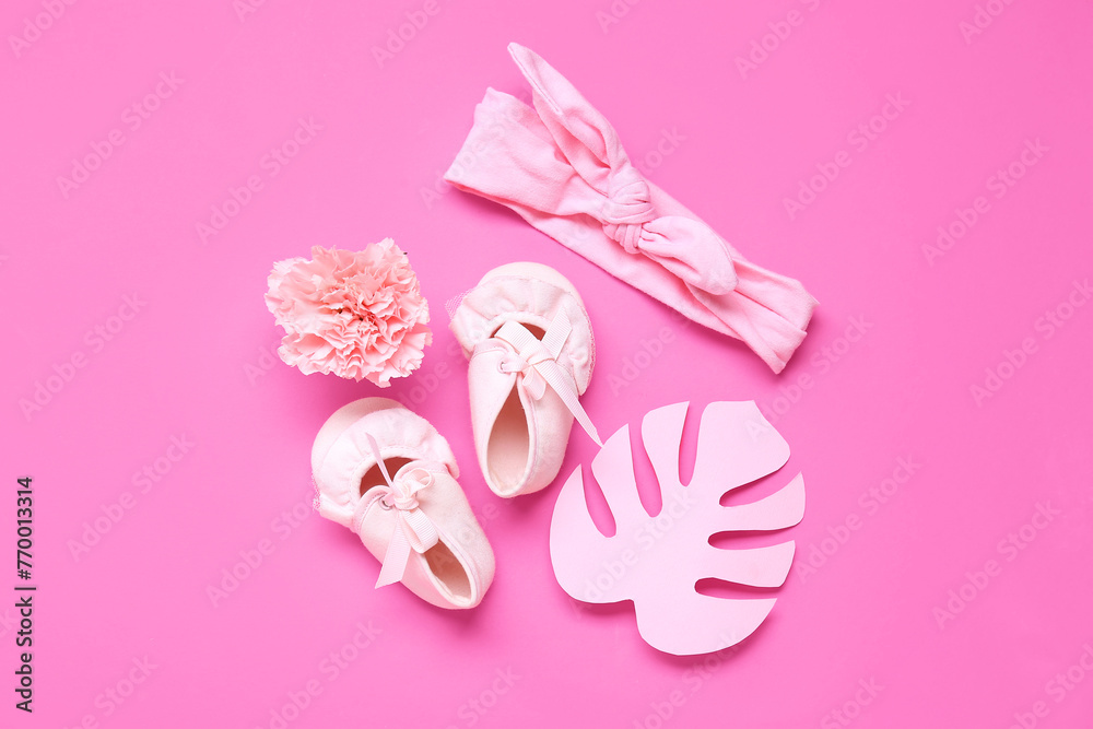 Composition with baby booties, headband and flower on pink background