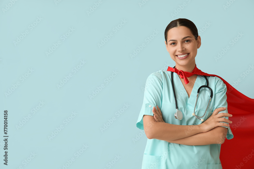 Beautiful female doctor in superhero costume on blue background Beautiful female doctor in superhero costume on blue background