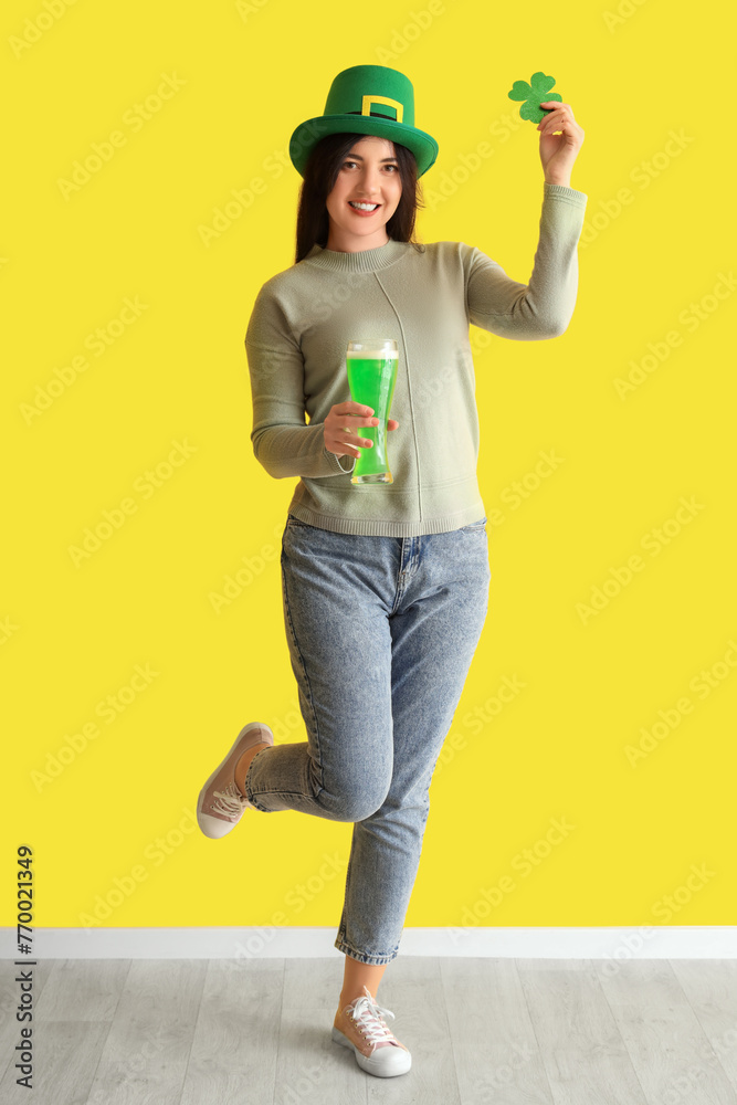 Young woman with beer and paper clover near yellow wall. St. Patrick's Day celebration Young woman with beer and paper clover near yellow wall. St. Patrick's Day celebration