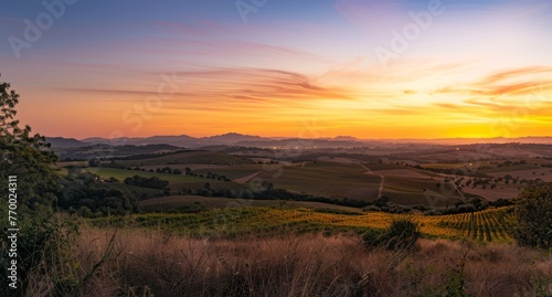 Panoramic rural sunset, with layers of hills fading into the distance under a sky ablaze with colors, providing a moment of awe and reflection on the day's end.