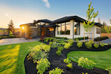 A state-of-the-art custom residence features a neat, green front lawn and modern landscaping in the late afternoon sun.