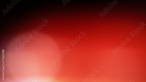 One light spot on a red background in a black frame, an abstract blurry background.