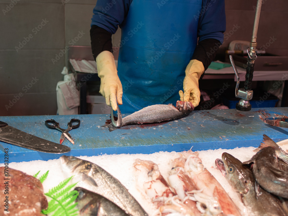 fishmonger scaling the fish in the fishmonger